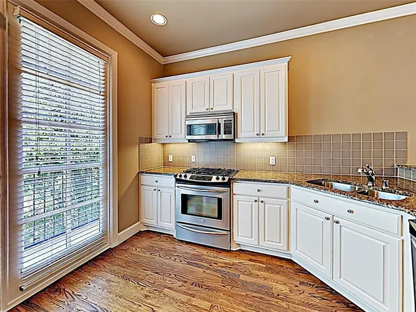 a kitchen with stainless steel appliances granite countertop a stove a sink and white cabinets