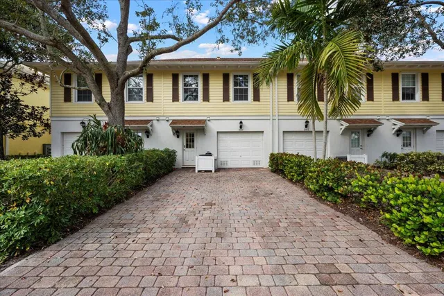a front view of a building with a garden and trees