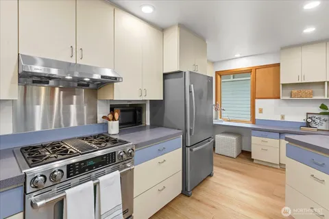 a dining hall with stainless steel appliances kitchen island granite countertop a sink a counter space and cabinets