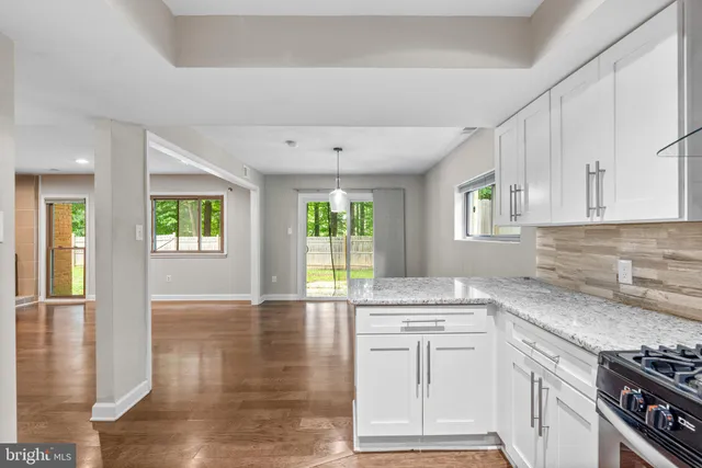 a kitchen with granite countertop a stove a sink and a refrigerator
