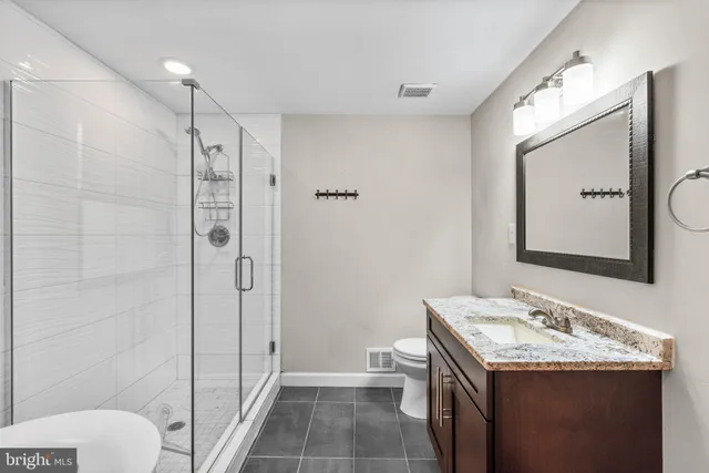 a bathroom with a granite countertop sink toilet and shower