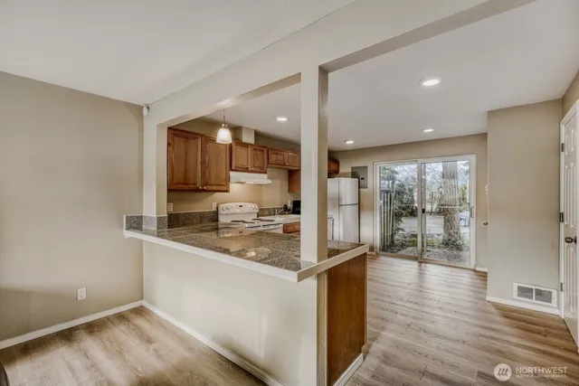 a kitchen with stainless steel appliances granite countertop a refrigerator a sink and a stove with wooden floor