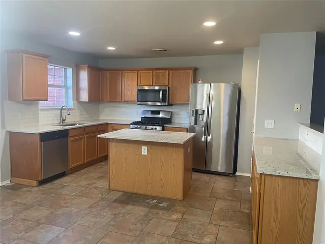 a kitchen with stainless steel appliances granite countertop a refrigerator sink and stove