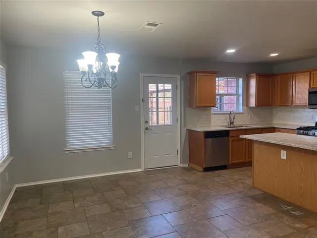 a large kitchen with kitchen island white cabinets stainless steel appliances a window and a fireplace