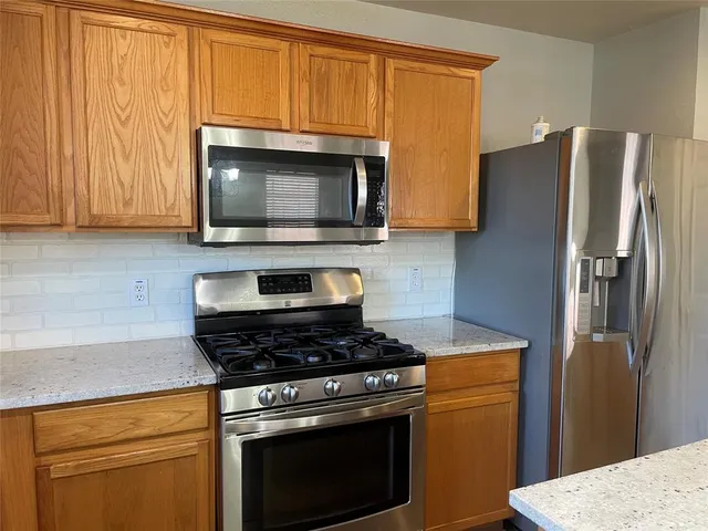 a kitchen with stainless steel appliances granite countertop a refrigerator stove and microwave