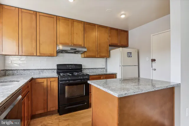 a kitchen with granite countertop wood cabinets stainless steel appliances and a counter space