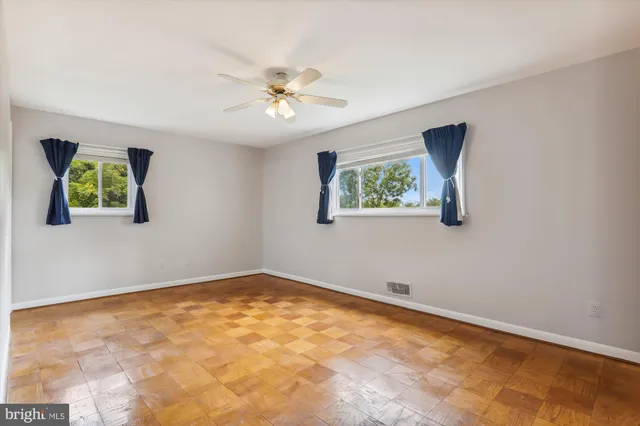 a view of empty room with wooden floor and fan