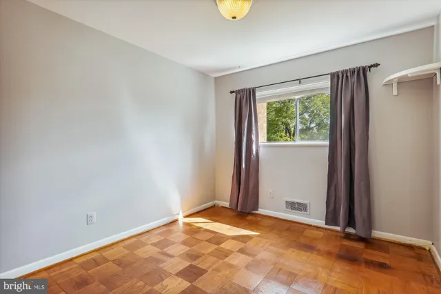 a view of an empty room with window and closet area