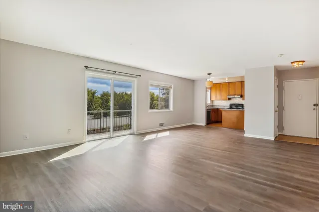 a view of empty room with wooden floor and a window