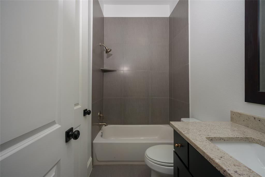 727 Will Rice Avenue Irving, TX 75039 - Photo 23 of 26 a bathroom with a granite countertop bathtub shower sink vanity mirror and toilet