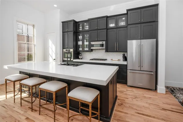 a kitchen with stainless steel appliances granite countertop a table chairs and a refrigerator