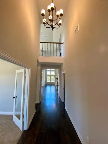 a view of a hallway with wooden floor and a chandelier