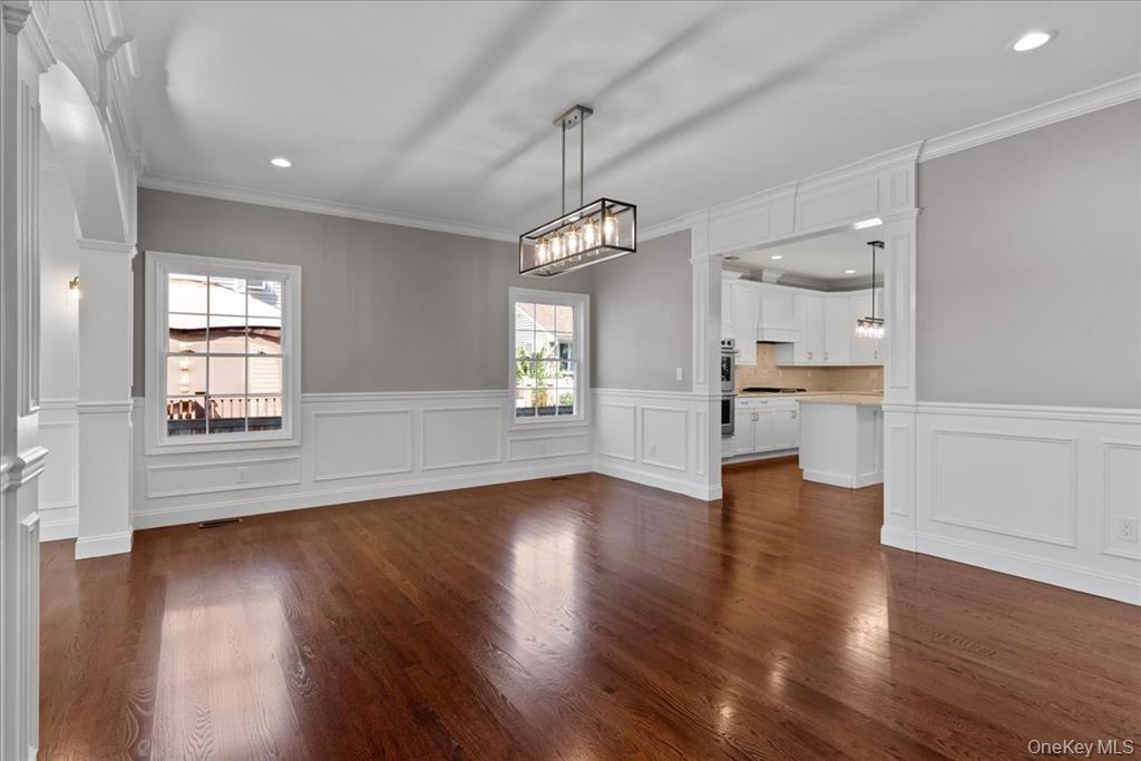 17 Hannington Avenue Wantagh, NY 11793 - Photo 9 of 29 Unfurnished dining area featuring dark wood-style flooring, decorative columns, recessed lighting, crown molding, and a decorative wall
