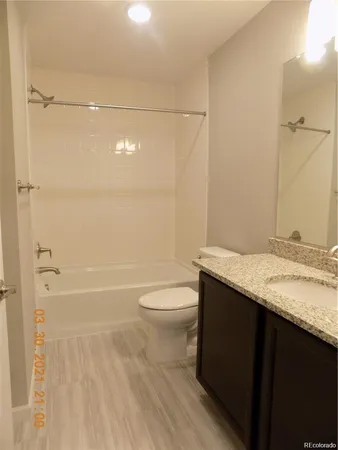 a bathroom with a granite countertop bathtub shower sink vanity and toilet
