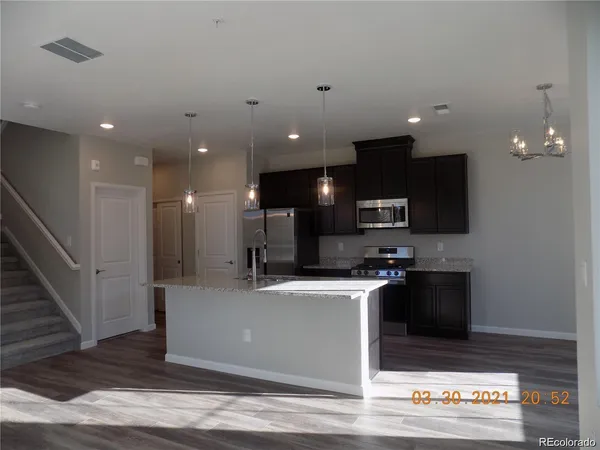 a view of a kitchen with stainless steel appliances kitchen island granite countertop a refrigerator and a stove top oven
