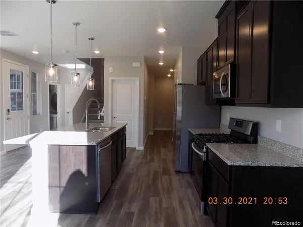 a kitchen with granite countertop a stove a sink dishwasher a refrigerator and wooden floor