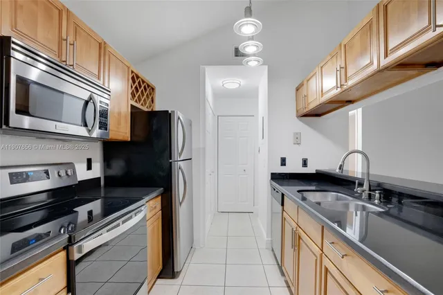 a kitchen with stainless steel appliances granite countertop a sink and a refrigerator