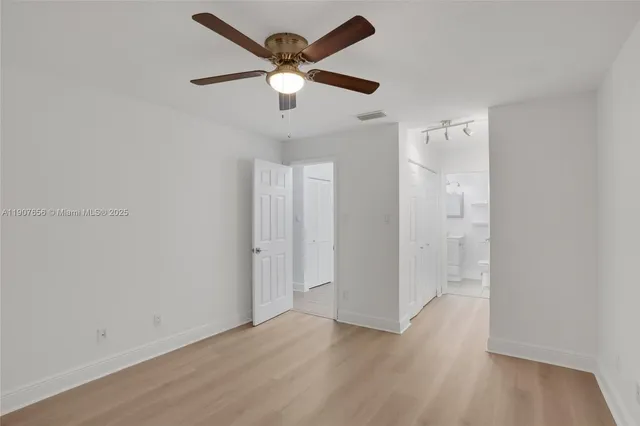 an empty room with wooden floor and a ceiling fan