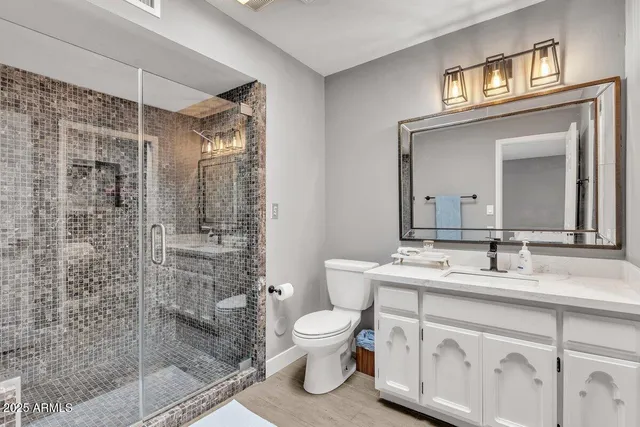 a bathroom with a granite countertop sink toilet a mirror and shower