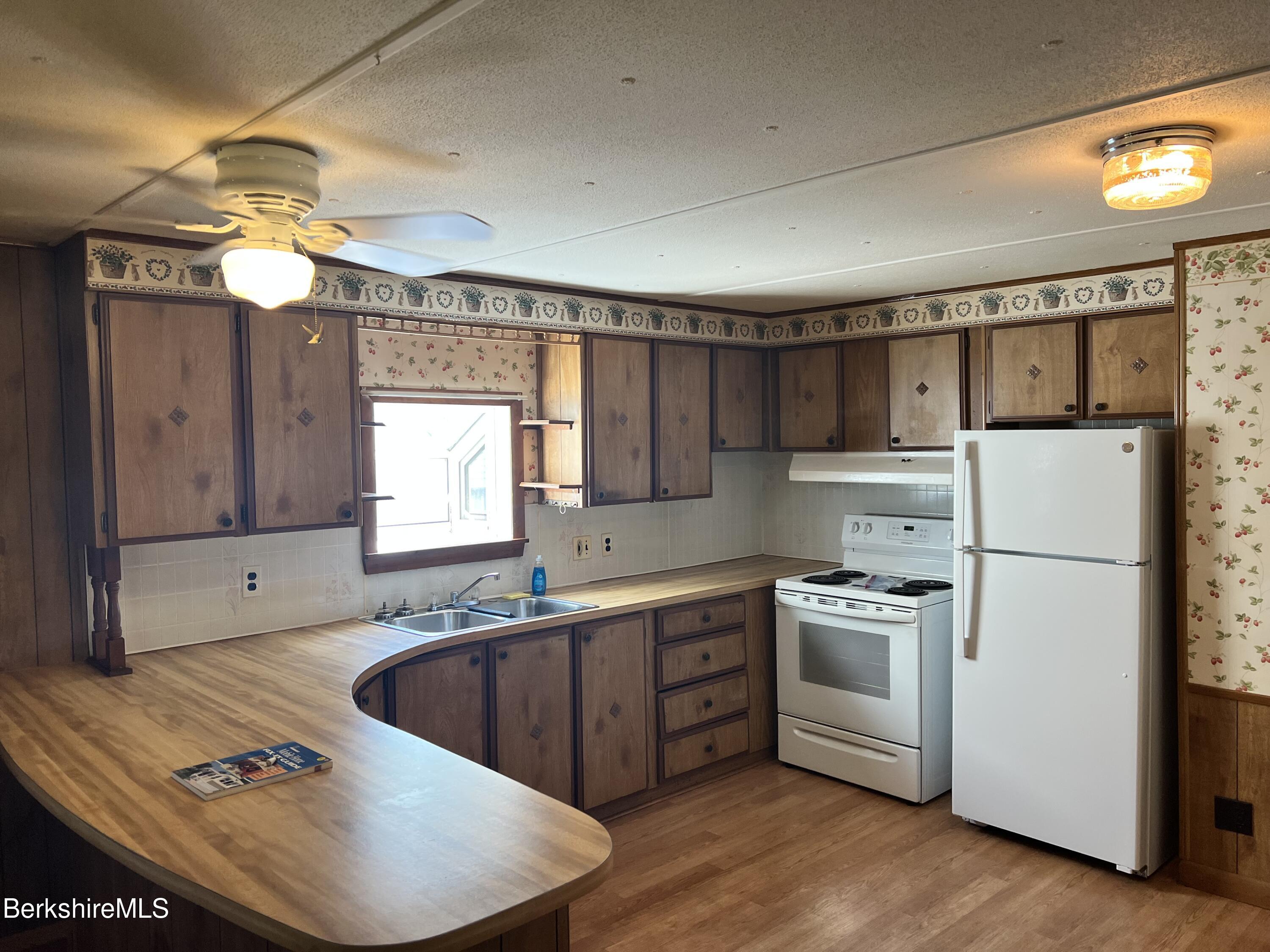 405 Pittsfield Road, Unit H12 Lenox, MA 01240 - Photo 2 of 13 a kitchen with stainless steel appliances granite countertop a sink a stove a refrigerator and island with wooden floor