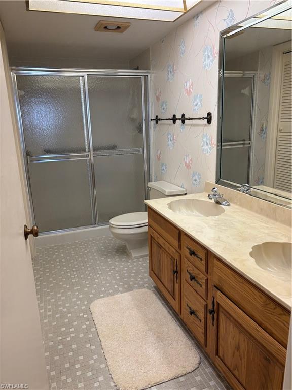 15 Bluebill Avenue, Unit 1006 Naples, FL 34108 - Photo 15 of 25 Bathroom with double vanity, wallpapered walls, and a shower stall
