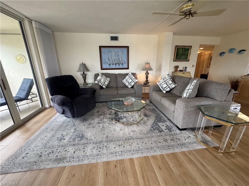 15 Bluebill Avenue, Unit 1006 Naples, FL 34108 - Photo 6 of 25 Living area with light wood-style flooring, ceiling fan, and floor to ceiling windows