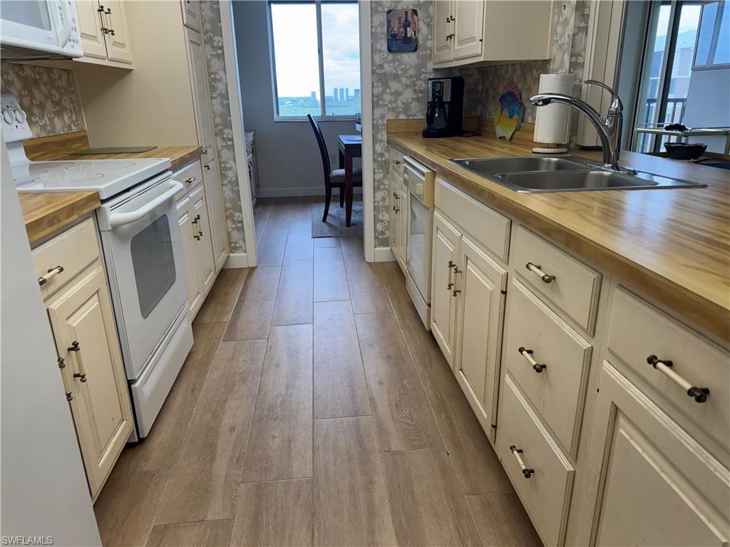 15 Bluebill Avenue, Unit 1006 Naples, FL 34108 - Photo 9 of 25 Kitchen with white appliances, tasteful backsplash, light wood-type flooring, and white cabinetry