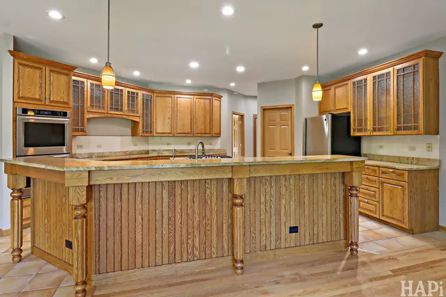 a kitchen with stainless steel appliances granite countertop a refrigerator a oven a sink and white cabinets with wooden floor