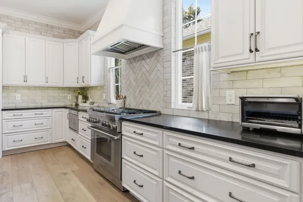 a kitchen with granite countertop white cabinets stainless steel appliances and a counter space