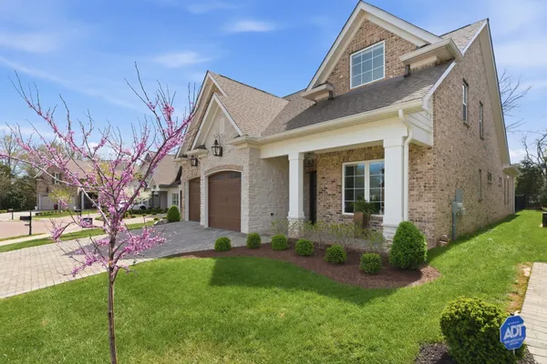 a front view of a house with a yard and potted plants