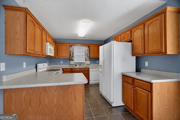 a kitchen with stainless steel appliances granite countertop a refrigerator a sink dishwasher and wooden cabinets with a dishwasher