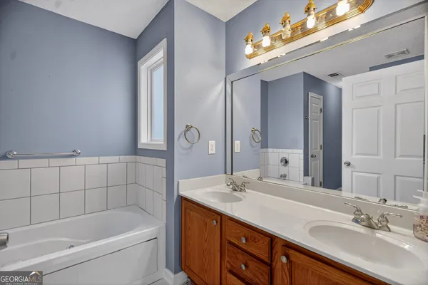 a bathroom with a tub a sink and mirror