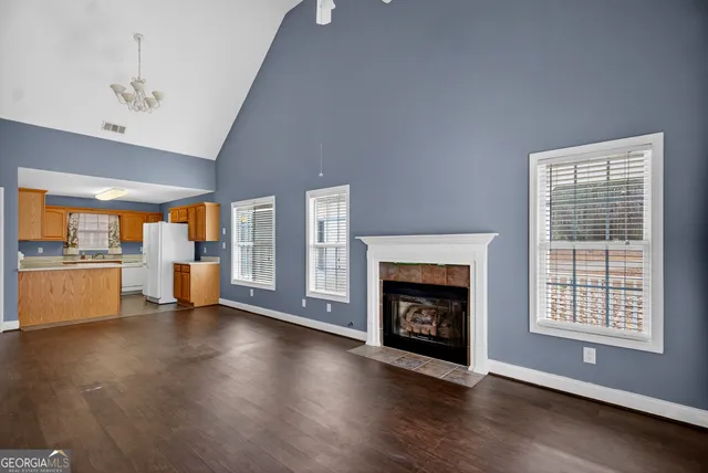an empty room with wooden floor fireplace and windows