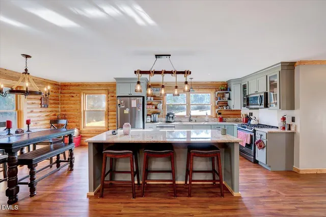 a kitchen with a counter top space a sink wooden floor and stainless steel appliances