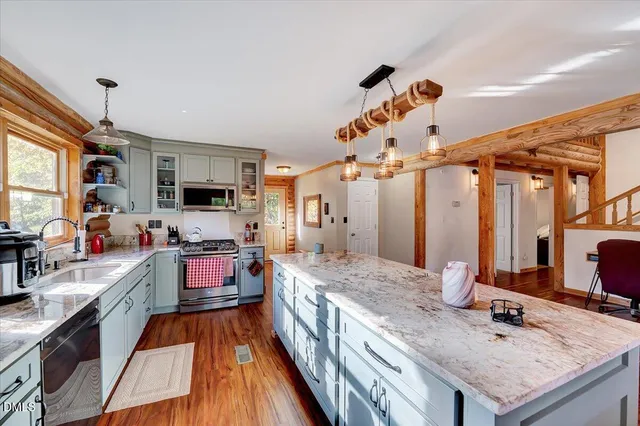 a kitchen with stainless steel appliances granite countertop a table chairs refrigerator and sink