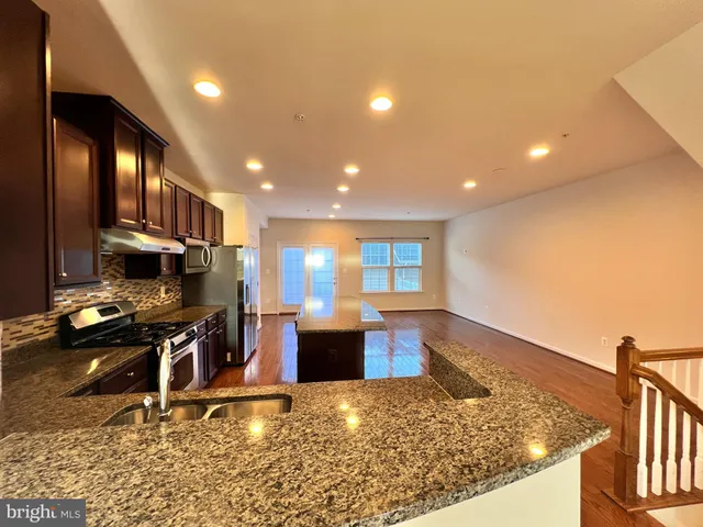 a kitchen with stainless steel appliances granite countertop a sink stove and wooden cabinets