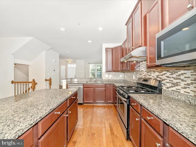 a kitchen with stainless steel appliances granite countertop a stove a sink and a microwave