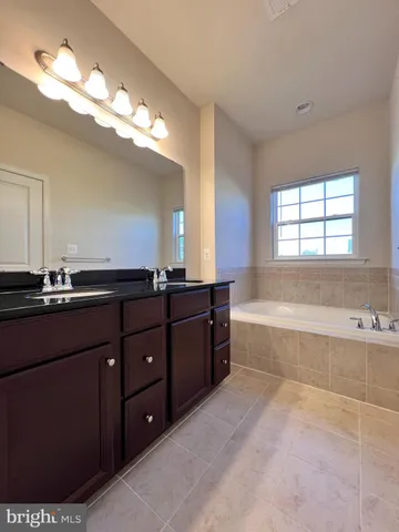 a spacious bathroom with a tub sink and mirror