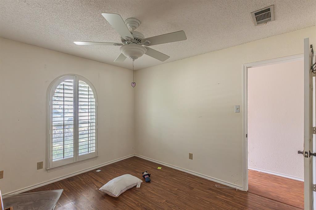 6504 Johnnie Street Watauga, TX 76148 - Photo 14 of 23 Room featuring an arched window with plantation shutters, wood-finish flooring, a ceiling fan, and painted walls