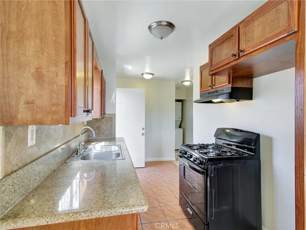 a kitchen with granite countertop a sink a stove and a wooden cabinets