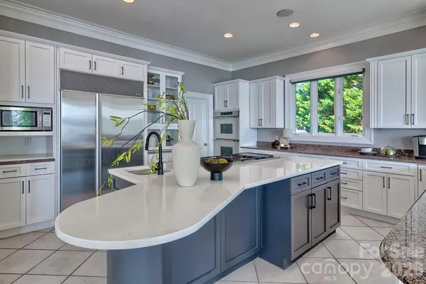 a kitchen with kitchen island granite countertop a sink stainless steel appliances and cabinets