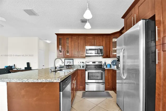 a kitchen with stainless steel appliances granite countertop a sink a stove a refrigerator a washer dryer and a dining table