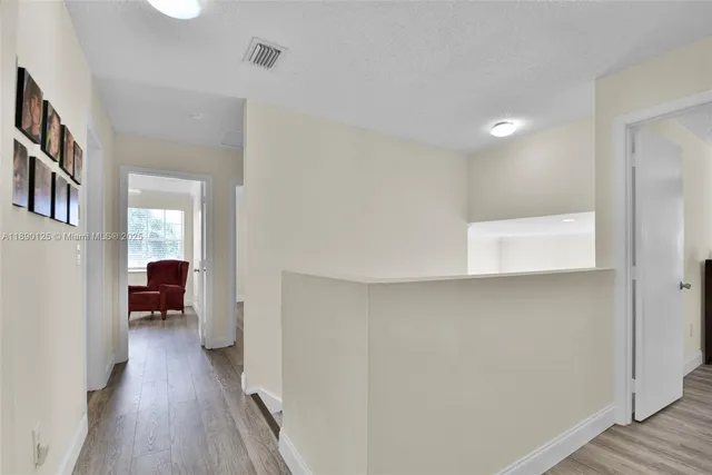 a view of a hallway with wooden floor and a living room