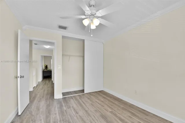 an empty room with wooden floor and a ceiling fan