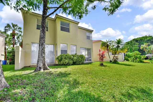 a front view of a house with a yard and palm trees