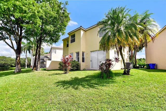a view of a house with a yard and palm trees