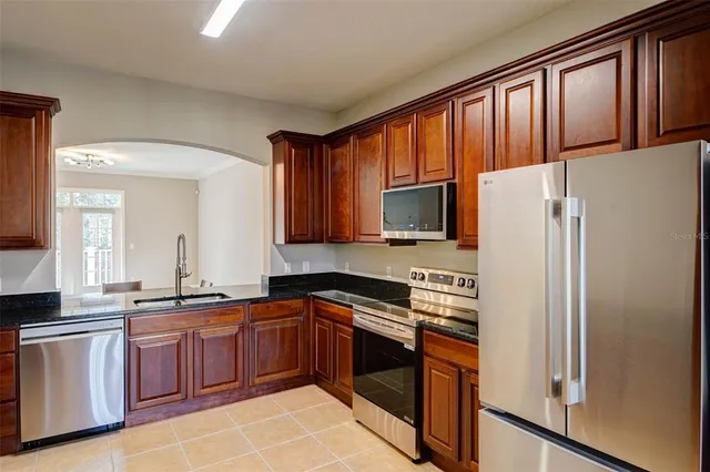 a kitchen with granite countertop a refrigerator stove top oven and sink