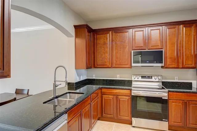a kitchen with granite countertop a sink stainless steel appliances and cabinets