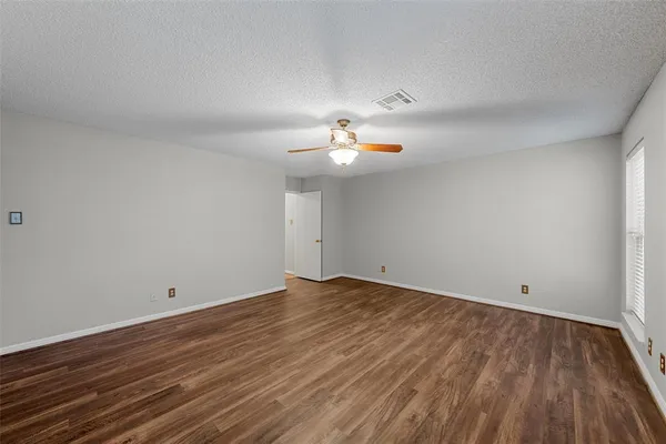 a view of a room with wooden floor and a ceiling fan