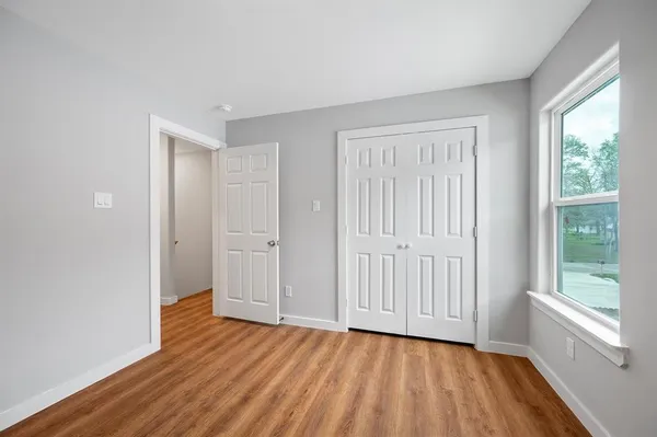 a view of an empty room with wooden floor and a window